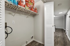 A hallway with a white door, a shelf with bags, and a black cable on the wall. - Cozy Modern 2BR/1BA • Birmingham Near Downtown (Homewood)