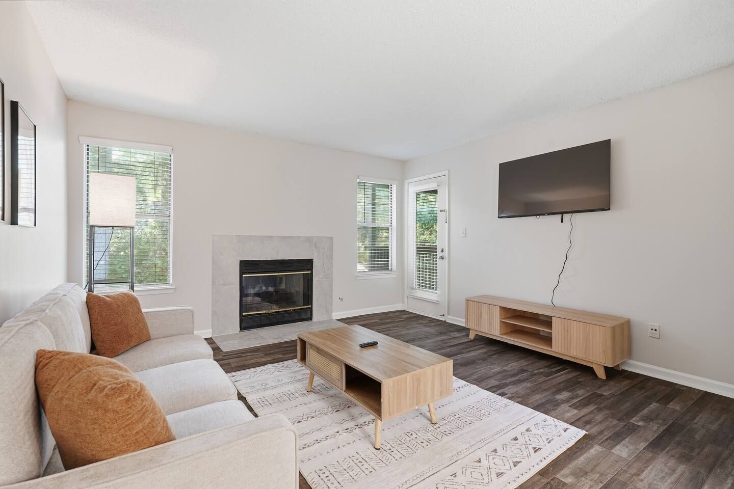 A modern living room with a fireplace, a sofa, a coffee table, and a TV.
