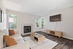 A modern living room with a fireplace, a sofa, a coffee table, and a TV.