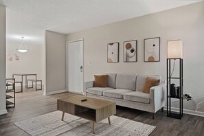 A modern living room with a sofa, coffee table, and artwork on the wall. - Cozy Modern 2BR/1BA • Birmingham Near Downtown (Homewood)