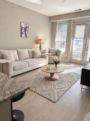 Een moderne woonkamer met een bank, salontafel en een schilderij aan de muur.