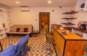 A compact living space with a sofa, a small bar area, and a patterned floor. - Humboldt | Loft with AC in the Historic District (Oaxaca de Juárez)