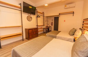 A hotel room with two beds, a TV, a mirror, and a small table with a chair. - Humboldt | Loft with AC in the Historic District (Oaxaca de Juárez)