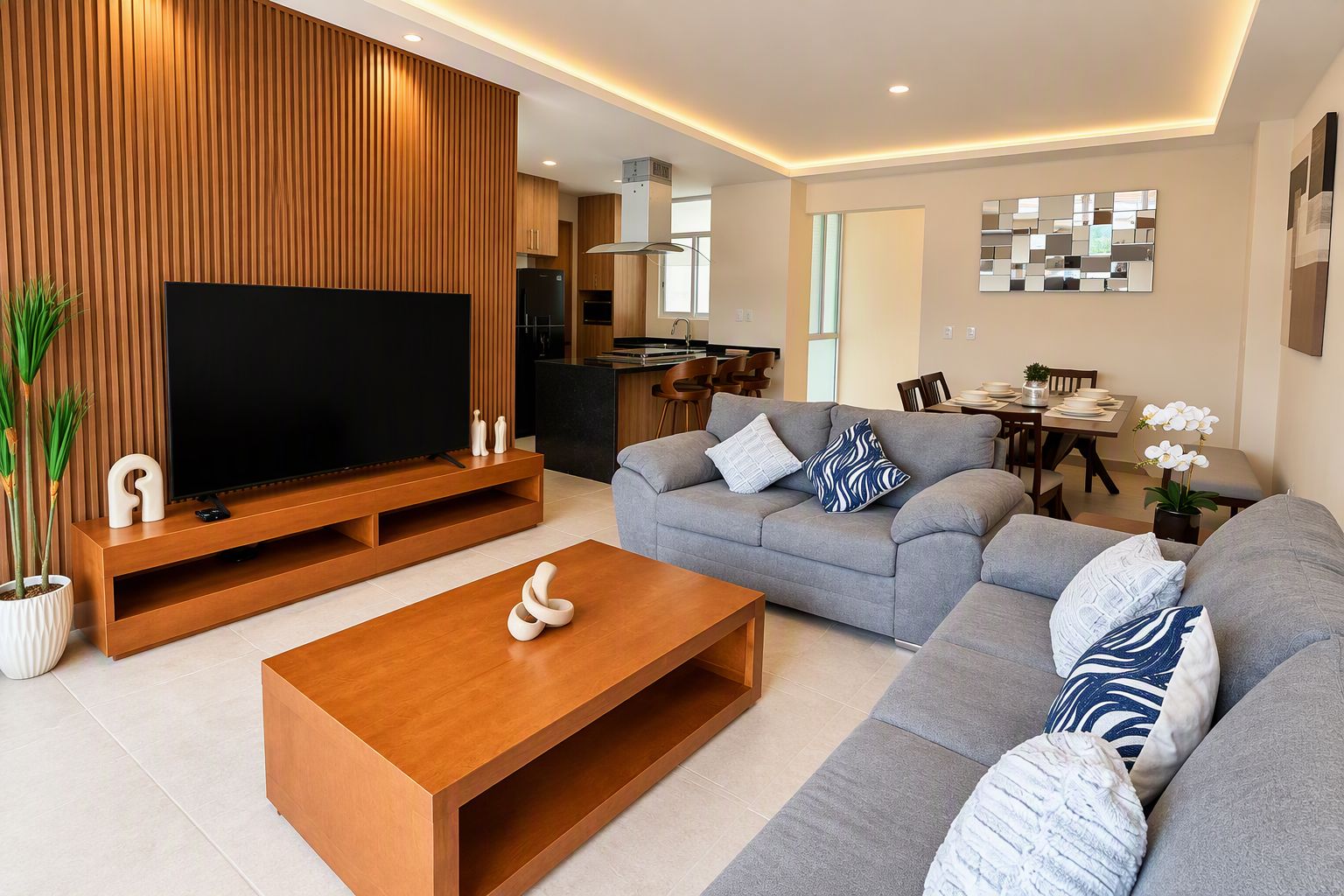A modern living room with a flat-screen TV, a wooden coffee table, and a grey sofa set.
