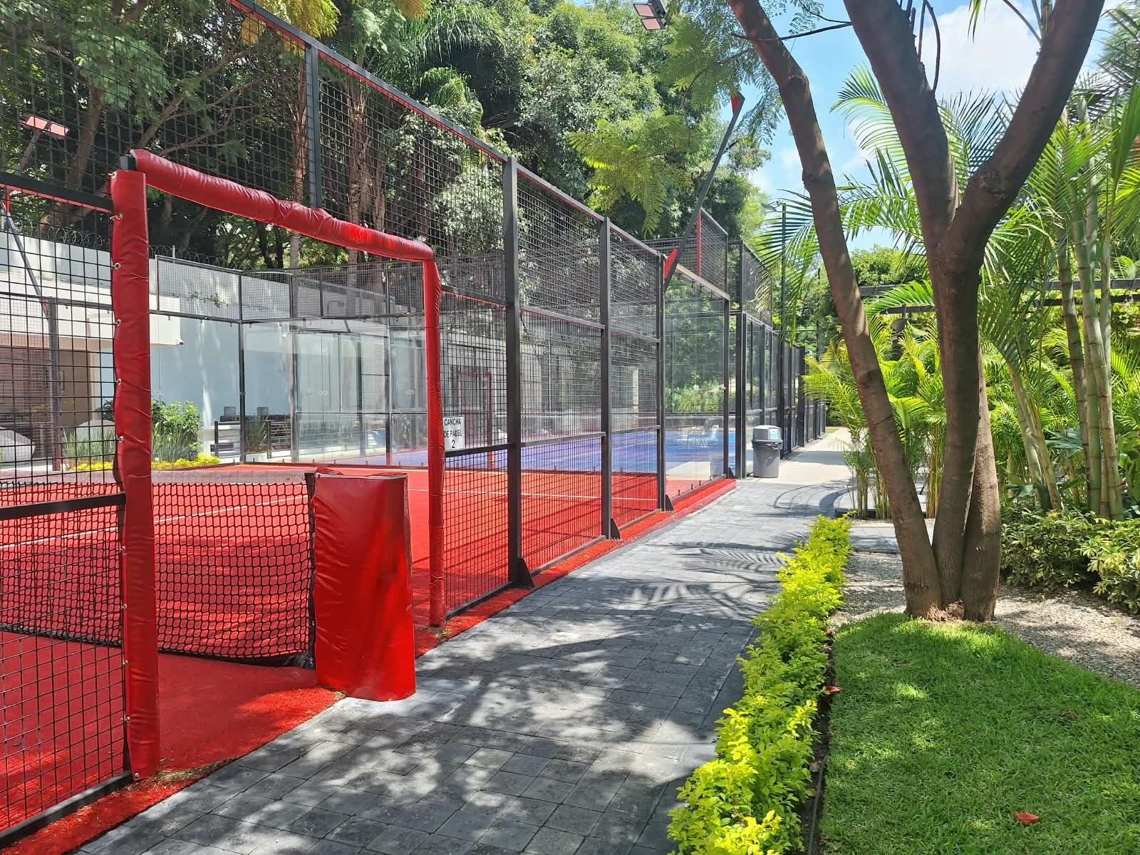 A sports facility with a fenced area, a netted goalpost, and a paved walkway.