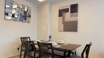 A dining area with a rectangular table, four chairs, and two wall-mounted abstract art pieces.