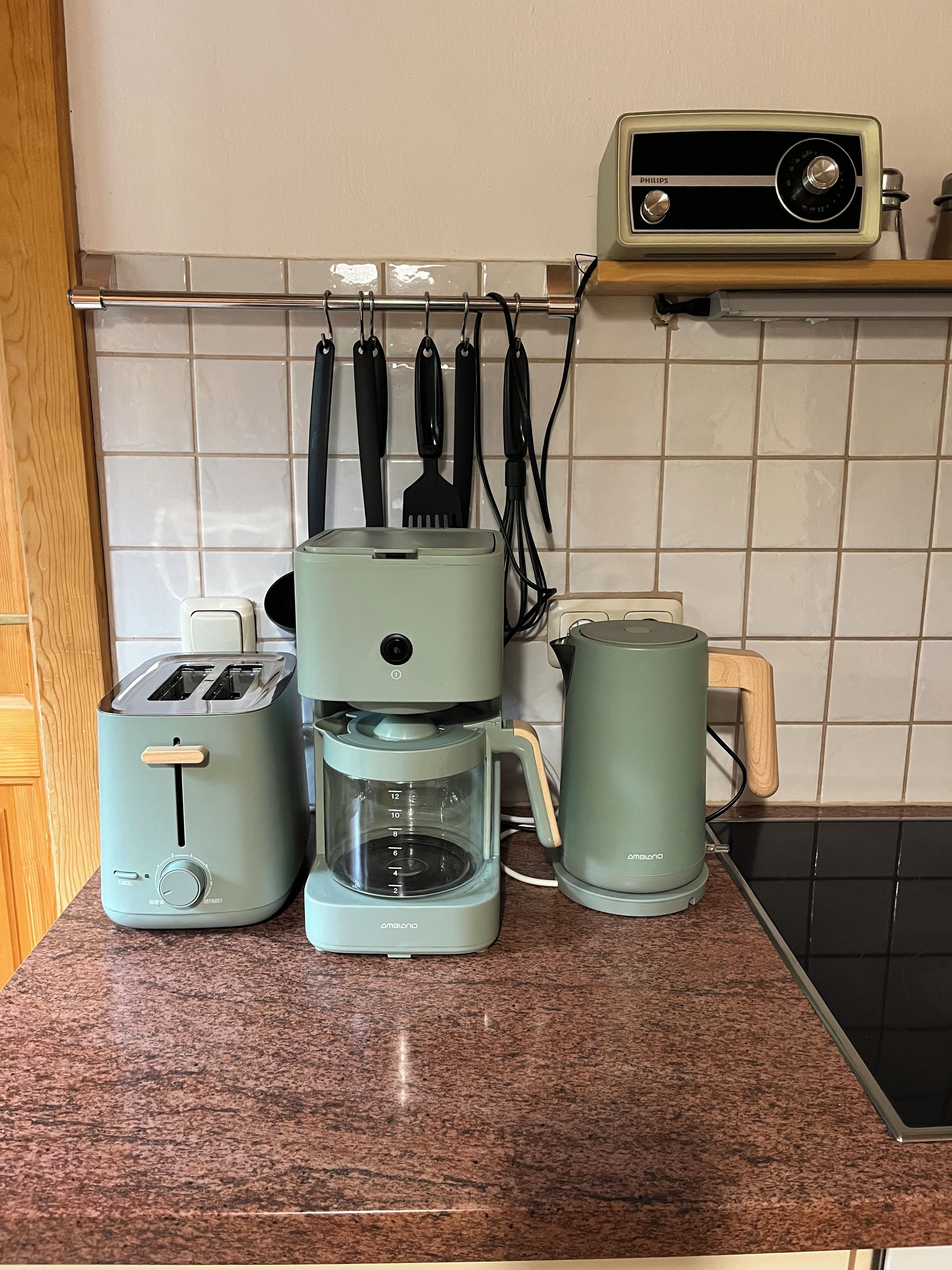 Una cocina con tostadora, cafetera y un radio Philips sobre la encimera.