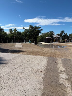 A paved area with a concrete pathway leading to a building, surrounded by trees and a clear sky. - Florida Farm House, Beaches, Boating, Fishing, Shopping, Restaurants, and Sports (Ellenton)