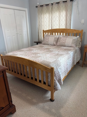 A bedroom with a wooden bed, a bedside table, a wardrobe, and a curtain. - Florida Farm House, Beaches, Boating, Fishing, Shopping, Restaurants, and Sports (Ellenton)