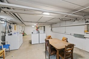 A laundry room with a table and chairs, washing machines, and a water heater. - Cozy 1-bedroom condo in delightful Oak Park with AC (Oak Park)