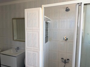 Ein Badezimmer mit einem weißen Waschbecken, einem Spiegel und einer Dusche mit Glastür.