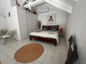 A bedroom with a bed, a chair, a rug, and a painting on the wall. - Charming duplex with swimming pool (Saint-François)
