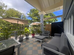 A covered outdoor seating area with a table, chairs, and potted plants. - Charming duplex with swimming pool (Saint-François)