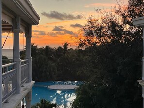 A pool surrounded by tropical vegetation and a building with a balcony. - Charming duplex with swimming pool (Saint-François)