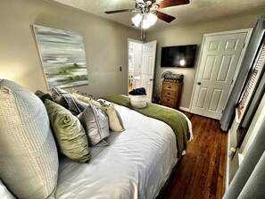 A bedroom with a bed, a ceiling fan, a painting, a dresser, and a television. - Cozy & Luxurious Whole Home Near Ft. Benning and Uptown (Columbus)