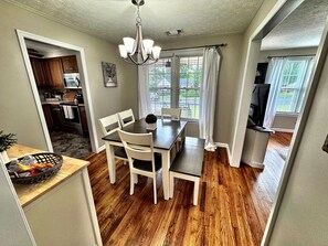 A dining area with a table, chairs, and a chandelier. There is a kitchen visible through an open doorway. - Cozy & Luxurious Whole Home Near Ft. Benning and Uptown (Columbus)