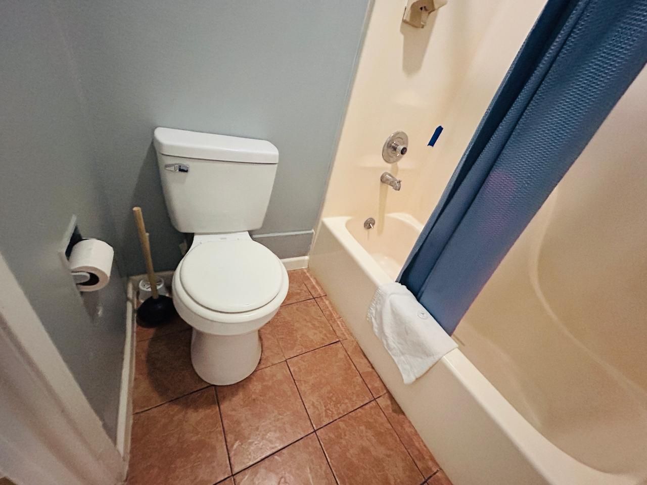 A bathroom with a toilet, a bathtub, and a shower curtain.