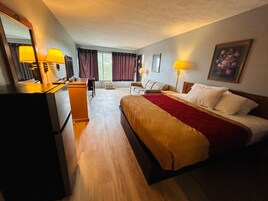 A hotel room with a bed, a desk, a chair, a television, and a window with curtains.