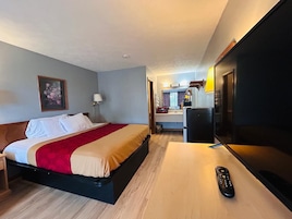 A hotel room with a bed, a desk, a television, and a mirror.