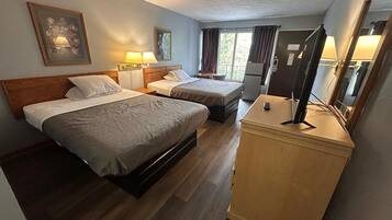 Habitación de hotel con dos camas, un escritorio, un espejo y una ventana con cortinas.