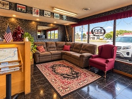 A hotel lobby with a sectional sofa, a red armchair, a large rug, and a map display.
