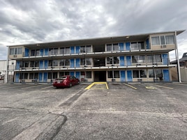A multi-story building with a parking lot in front.
