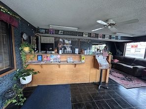 A reception area with a wooden counter, a ceiling fan, and a couch in the background.