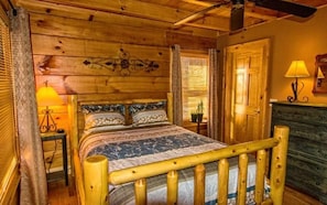 Dormitorio de cabaña de madera con cama, mesita de noche, lámpara y cómoda.