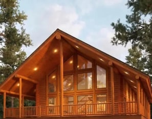 Una cabaña de madera con balcón, ventanas amplias y una escalera que lleva al nivel superior.