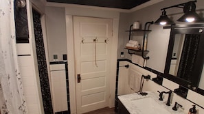 Un bagno con una porta bianca, un lavandino con uno specchio e un porta asciugamani.