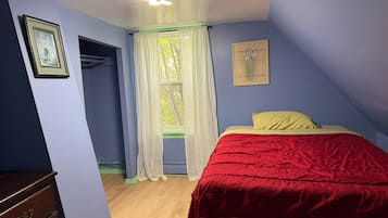 A bedroom with a bed, a window with curtains, a dresser, and a ceiling fan.