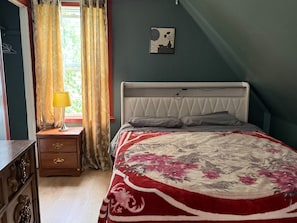 A bedroom with a bed, a nightstand, a lamp, a window with curtains, and a wall-mounted picture. - Home in North Sydney near ferry (North Sydney)