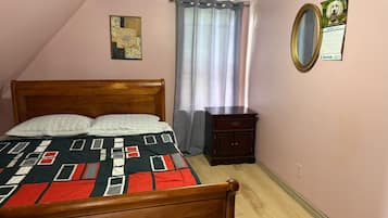 A bedroom with a wooden bed, a nightstand, a mirror, and a calendar on the wall.