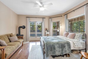 Une chambre à coucher comprenant un lit, un canapé, un ventilateur de plafond et offrant une vue sur l’extérieur grâce à de grandes fenêtres.