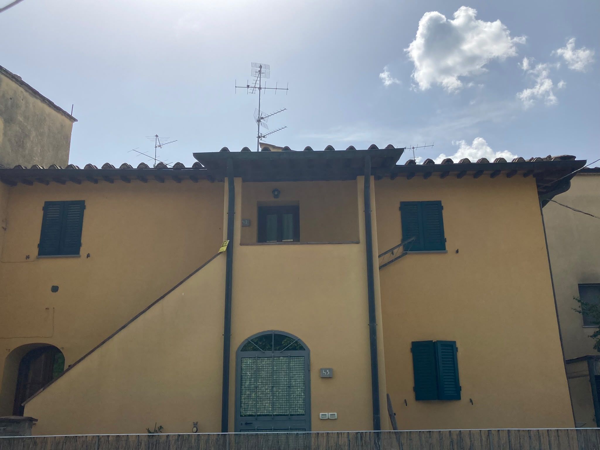 Un edificio con facciata gialla, un ingresso centrale e diverse finestre con persiane.