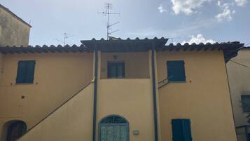 Un edificio con facciata gialla, un ingresso centrale e diverse finestre con persiane.