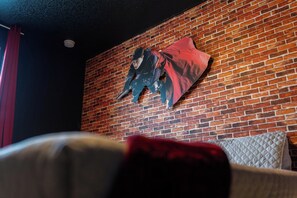 A room with a brick wall, a bed with a white headboard, and a red pillow. - 3BR Townhome | Themed Room + Pool | Gated (Kissimmee)