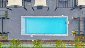 An aerial view of a rectangular swimming pool with a surrounding deck area, including lounge chairs and umbrellas. - 3BR Townhome | Themed Room + Pool | Gated (Kissimmee)