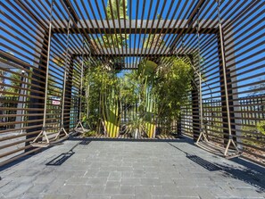 A covered walkway with a wooden frame and rope swings, surrounded by bamboo plants. - 3BR Townhome | Themed Room + Pool | Gated (Kissimmee)