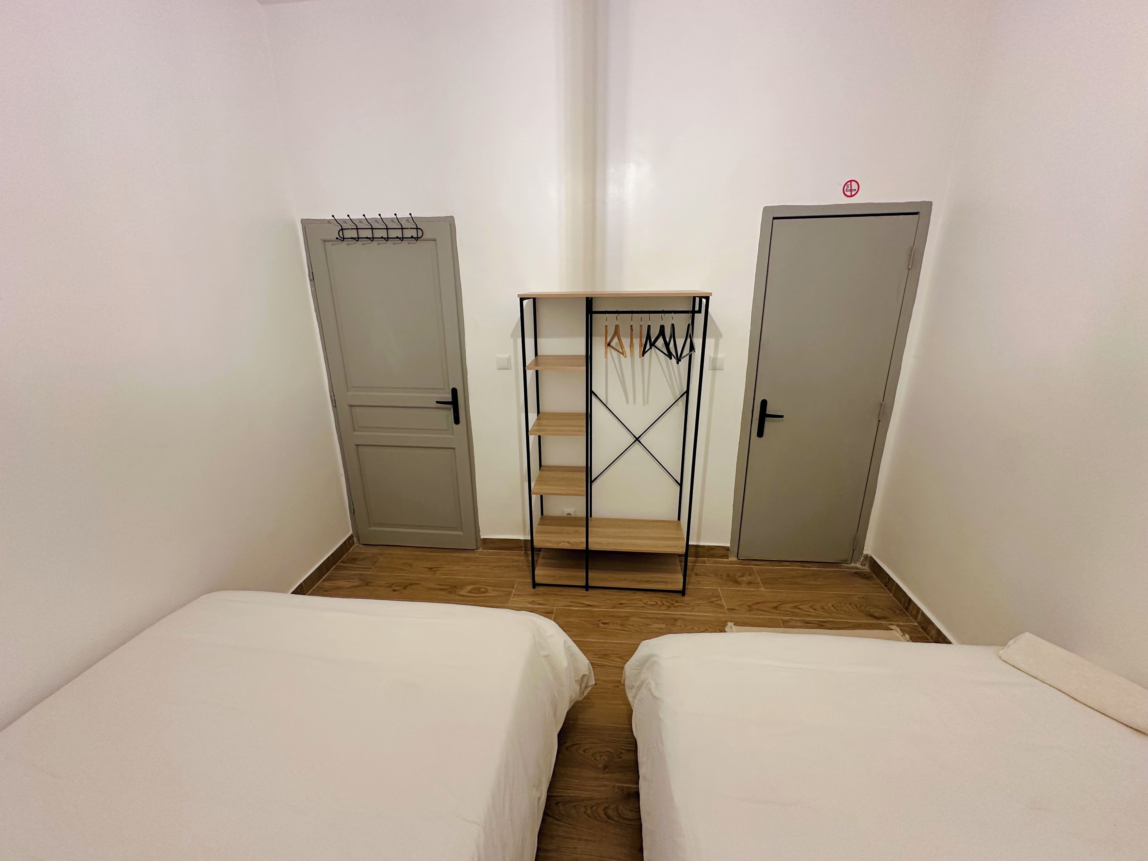 Ein Zimmer mit zwei Betten, einem Kleiderschrank und einer Kleiderstange.