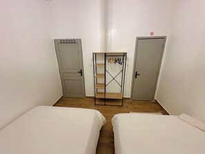 Ein Zimmer mit zwei Betten, einem Kleiderschrank und einer Kleiderstange.