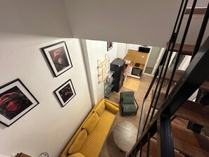 Ein modernes Interieur mit einem gelben Sofa, einem runden Hocker und gerahmten Kunstwerken an den Wänden.