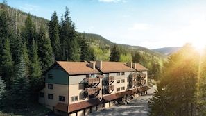 Een hotel met meerdere verdiepingen en balkons, gelegen in een bebost berglandschap.