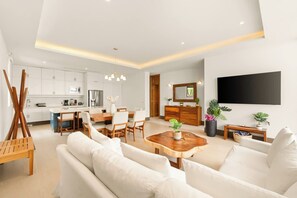 Ein moderner Wohnraum mit Essbereich, Küche und einem an der Wand befestigten Flachbildfernseher.