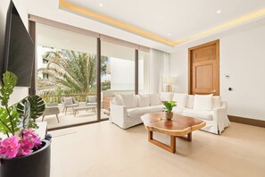 A modern living room with a white sofa, a wooden coffee table, and a large window overlooking a tropical garden. - Jungle Oasis 2BR | Luxury Beach Club + 5 Pools (Cruz de Huanacaxtle)