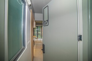 A hallway with a door marked '07' leading to a room with a view of greenery outside. - Study with a large window · Featured design (H07) (Providencia)