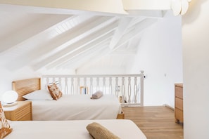 A bedroom with two beds, a wooden headboard, a nightstand, a dresser, and a white railing. - Charming duplex with a view of the marina and the cistern (Le Gosier)