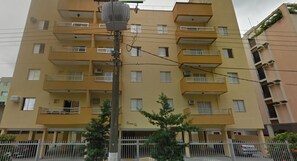 A multi-story residential building with balconies, a streetlight, and a fence. - Apartment in Guarujá - Enseada Beach - Excellent (Guarujá)