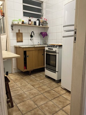 Een kleine keuken met een fornuis, oven en een klein aanrecht.