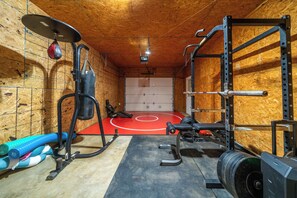 A gym with weightlifting equipment, a wrestling mat, and a blue water bottle on the floor. - Private Lakefront Retreat | Pool, Hot Tub, Kayaks (Hot Springs)